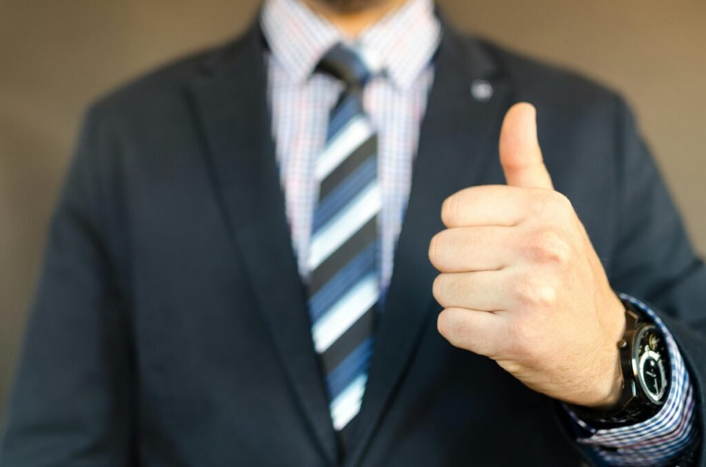 pexels photo 653429 653429 Close-up of a businessman in a suit giving a thumbs up gesture, symbolizing success.